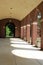 Sun and shade streaming through arched brick and stone hallway