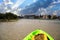 Sun shines through the clouds over a Green Kayak in the water of New Pass in Bonita Springs