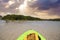 Sun shines through the clouds over a Green Kayak in the water of New Pass in Bonita Springs