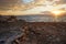 Sun shines through dramatic sunset clouds to waves at Jordanian side of Dead Sea, branches, flotsam, debris and rubbish washed on