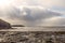 Sun shines over ocean and rugged stone coastline. West coast of Ireland. Irish seascape. Stunning cloudy sky with rays of light