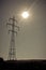 Sun shining above high voltage power lines on power pylon