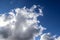 Sun shining behind the fluffy white cloud formations in a deep blue summer sky