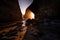 the sun is shining behind two large boulders at low tide