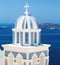Sun shining through belltower of church with a view of Santorini volcanic caldera and ships in it, Santorini, Cyclades