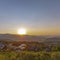 Sun shining on valley with homes hills square