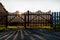 Sun is shining through wooden gate at dawn in summer.