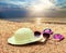 Sun straw hat, book, flip flop sandals and sunglasses lying on the beach