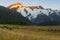 Sun at sunrise strikes snow-capped mountain peaks beyond silhouette of foreground hills of Southern Alps, Canterbury New Zealand