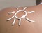 Sun symbol written in sunlotion on womans shoulder