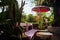 Sun umbrella and tables at cafe in tropical paradise. Space for chilling and green thick at backyard patio. Restaurant