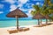 Sun umbrellas and beach beds under the palm trees on tropical beach