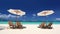 Sun umbrellas and beach chairs on coastline with white sand