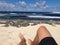 Sunbathing with legs stretching across beach towards the sea