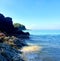 Sunbathing on rocks on the secluded beach. Light steaming through the trees. Cool and romantic place for relaxation.