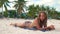 Sunbathing woman lying on towel on summer beach on luxury villa background. Attractive woman sun tanning on sandy beach