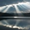 Sunbeam breaks through clouds, casting radiant glow over tranquil lake