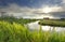 Sunbeams over house, river and meadow