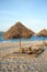 Sunbed and nipa sun umbrella on the white sand beach during sunset