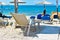 Sunbed in the sand by the beach under umbrella facing blue sea and clear sky