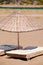 Sunbeds and rattan parasols on sandy seaside.