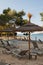 Sunbeds and thatched sunshades on the beach of a hotel with swimming pool and view to the sea on Ibiza island. Beautiful