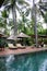 Sunbeds and umbrellas near the swimming pool and palm trees around it. Seascape of Indonesia.