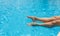 Sunburned female legs, splashes, clear turquoise pool water