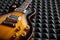 Sunburst electric guitar lying on acoustic foam panel background