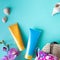 Suncare bottles, glasses, starfish, palm leaves, swimsuit and beach bag on a blue background. Beauty and care in the summer.