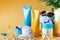 Suncare bottles, glasses, starfish palm leaves on a yellow background. Beauty and care in the summer. Copy space