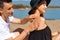 Suncare couple on a summer beach vacation have good skincare with high spf sunblock. Couple applying suncream. Handsome man