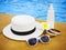 Suncream, sunglasses, hat, bracelet near the swimming pool