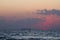 Sundawn on the Black Sea, sun disk appear on horizon with some clouds, early morning, gentle waves on water surface, cargo ship