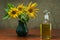 Sunflower oil in a glass decanter and a sunflowers in a vase on a background of burlap