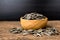 Sunflower seeds group with a wooden cup on wood background. The name of science : Helianthus annuus