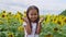 Sunflowers eyes. Adorable little girl holding Sunflowers in eyes like binoculars in the garden. Closeup kid portrait, baby closes