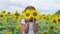 Sunflowers eyes. Adorable little girl holding Sunflowers in eyes like binoculars in the garden. Closeup kid portrait, baby closes