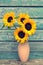 Sunflowers in the vase against old wooden wall