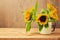 Sunflowers in vintage cup on wooden table.
