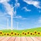 Sunflowers with wind turbine on green grass field against blue s