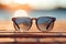A sunglass on wooden board on blur beach with bokeh background