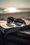 Sunglasses on a book with a beach behind, Generative AI