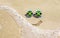 Sunglasses with flag of Jamaica on a sandy beach. Nearby is a sea lightning and a painted smile.