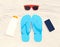 Sunglasses, frameless smartphone, sunscreen bottle, red flip flops