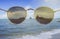 Sunglasses front of the camera,looked like wearing a sunglasses,blurred sea in background,selective focusat center of sunglasses