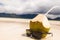 Sunglasses near coco nut with a straw on the beach