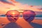 Sunglasses rest on sandy beach, framing vibrant ocean sunset