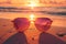 Sunglasses rest on sandy beach, framing vibrant ocean sunset