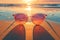 Sunglasses rest on sandy beach, framing vibrant ocean sunset